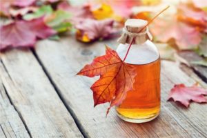 Pure maple syrup next to maple leaves