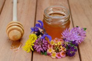 Wildflower honey in a jar next to flowers